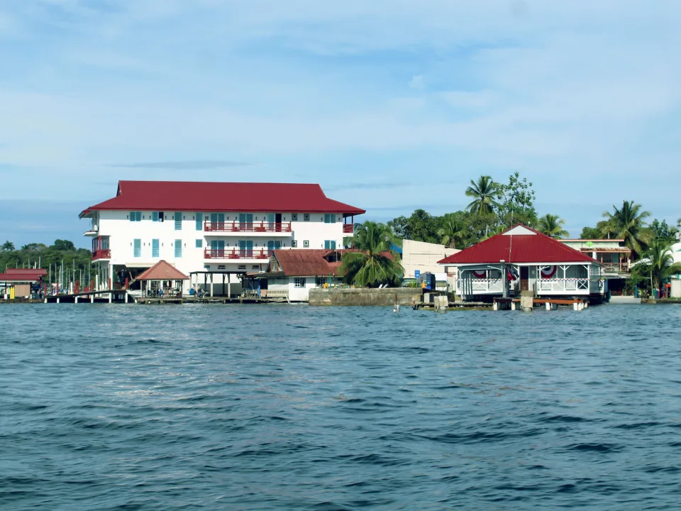 Red-roof waterfront buildings and palms beside blue water in Bocas del Toro, Panama