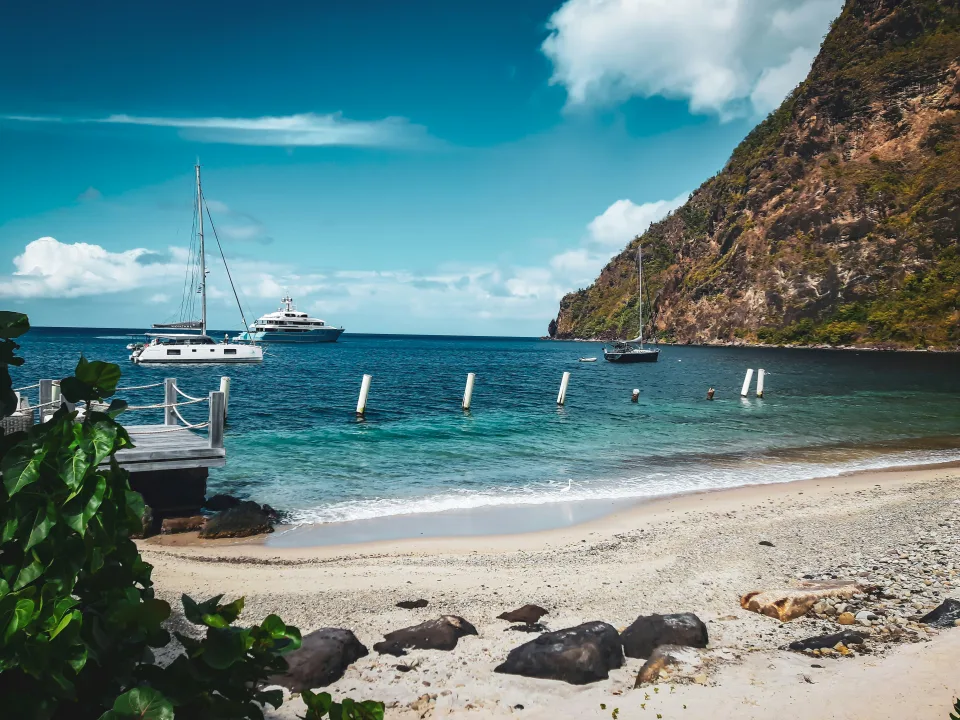 Anchored boats beside a beach and steep coastal rock at Soufriere, Saint Lucia