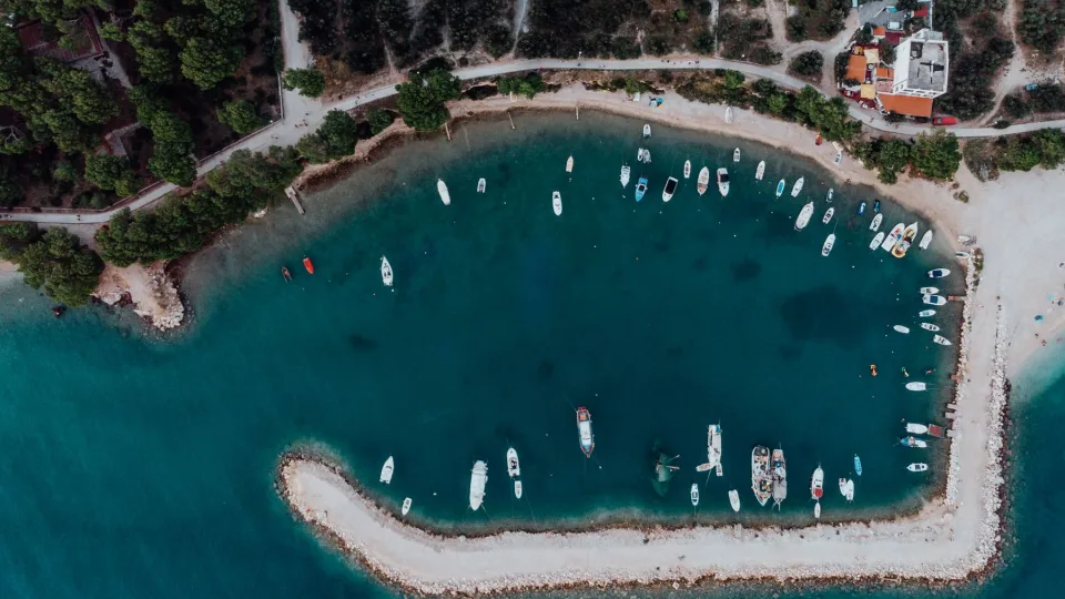 Boats moored in a sheltered Croatian coastal cove seen from above.