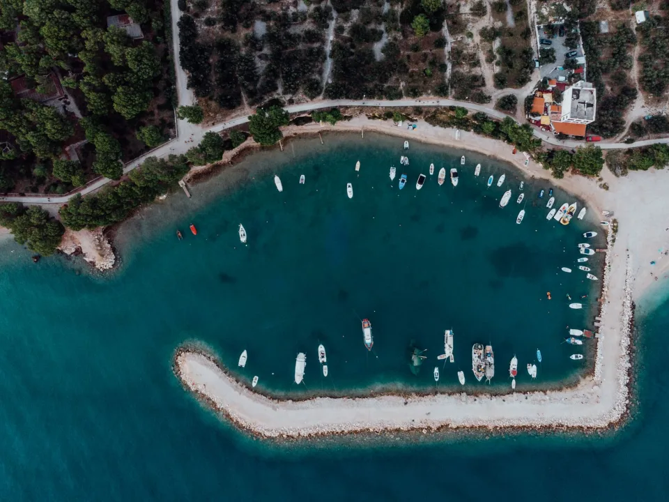 Boats moored in a sheltered Croatian coastal cove seen from above.