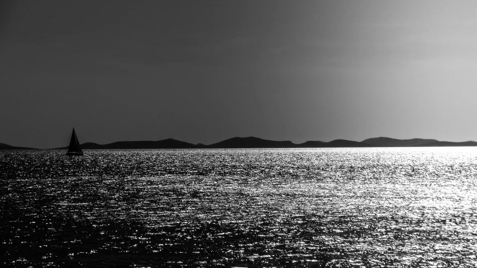 A sailboat off Murter in a black and white seascape.