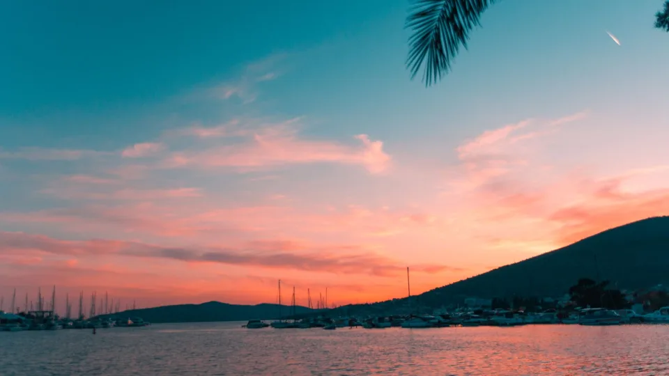 Sailboat masts along the Dalmatian coast at sunset.