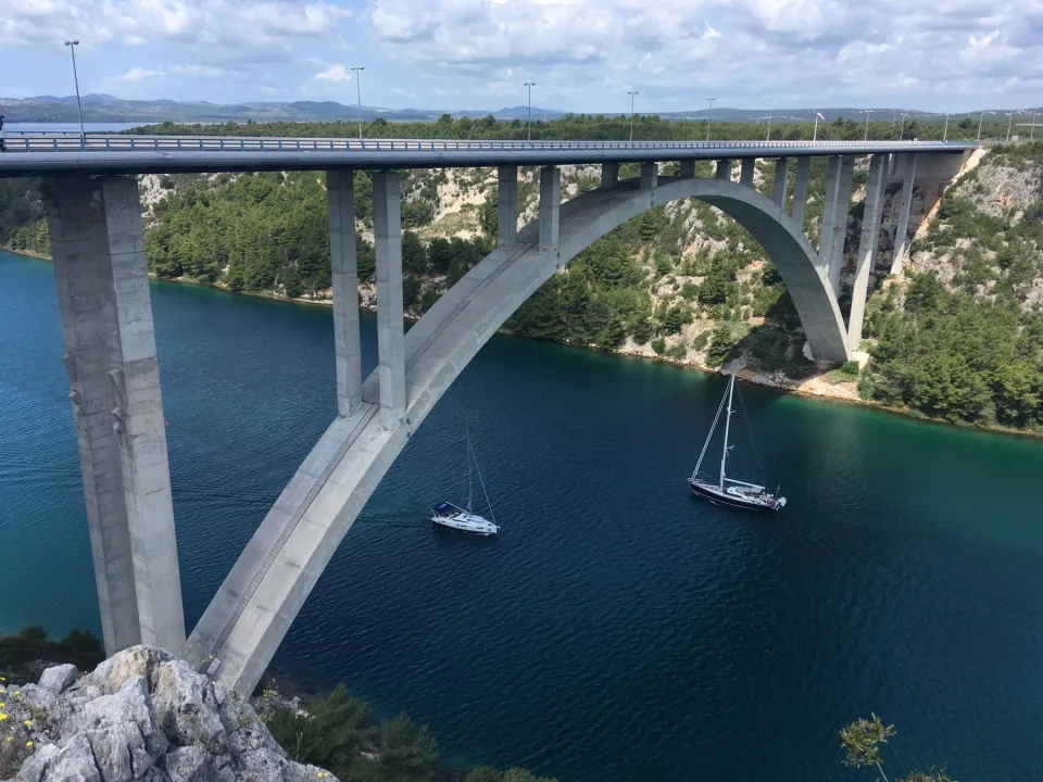 Boats on the river near Skradin beneath an arched bridge.