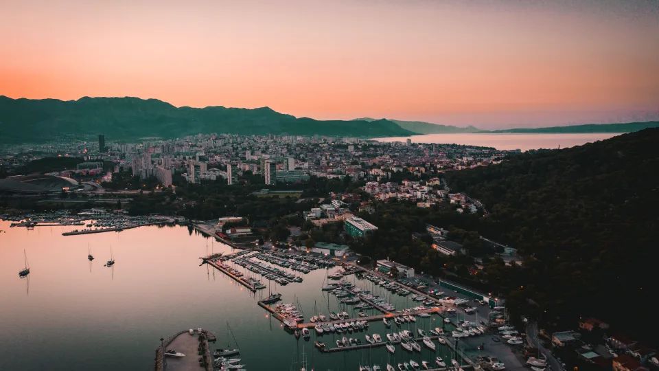 Aerial view of marina pontoons and Split city at dusk.