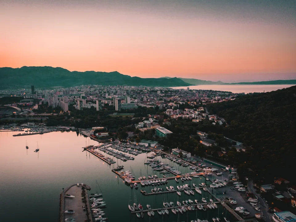 Aerial view of marina pontoons and Split city at dusk.