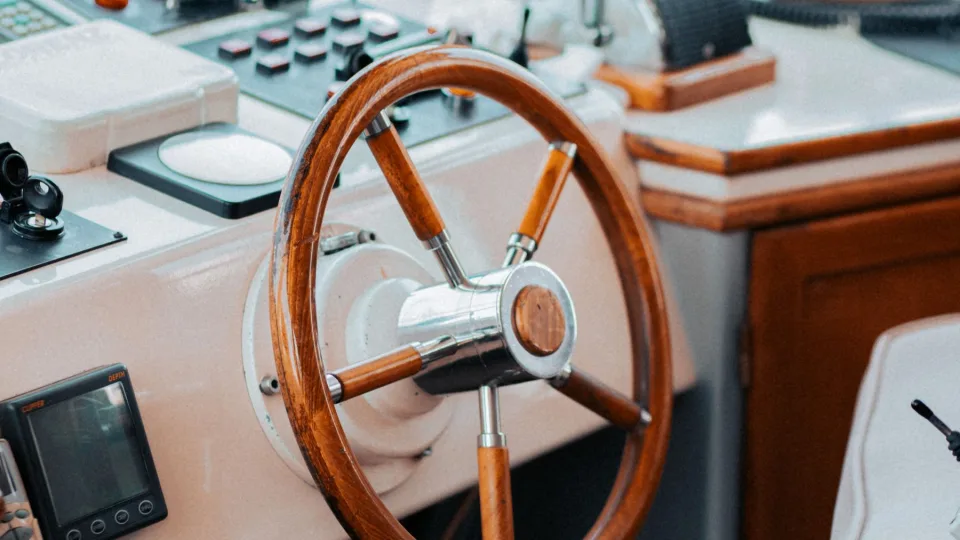 A yacht helm with steering wheel and navigation instruments.