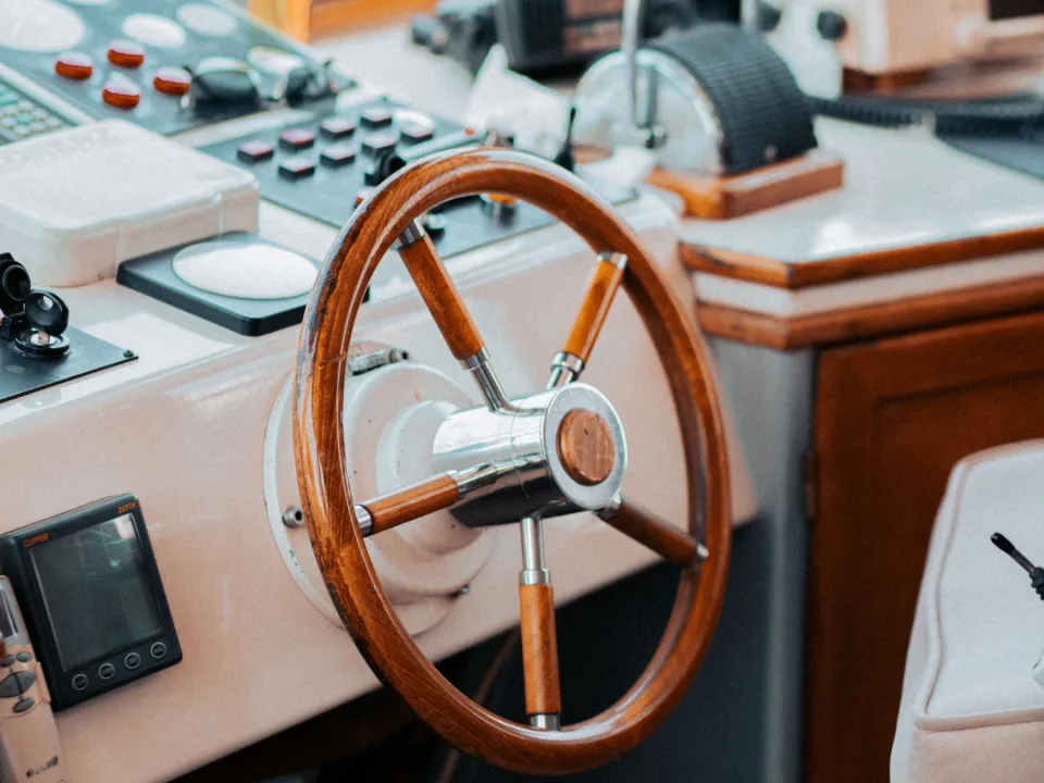 A yacht helm with steering wheel and navigation instruments.
