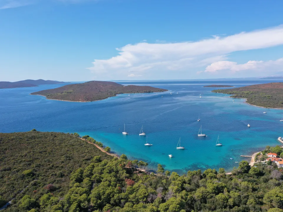 Sailboats anchored between wooded islands in a Croatian bay.