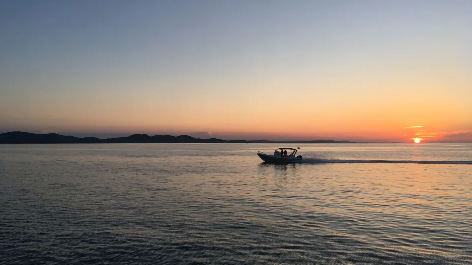 A small motorboat crossing the Adriatic at sunset.
