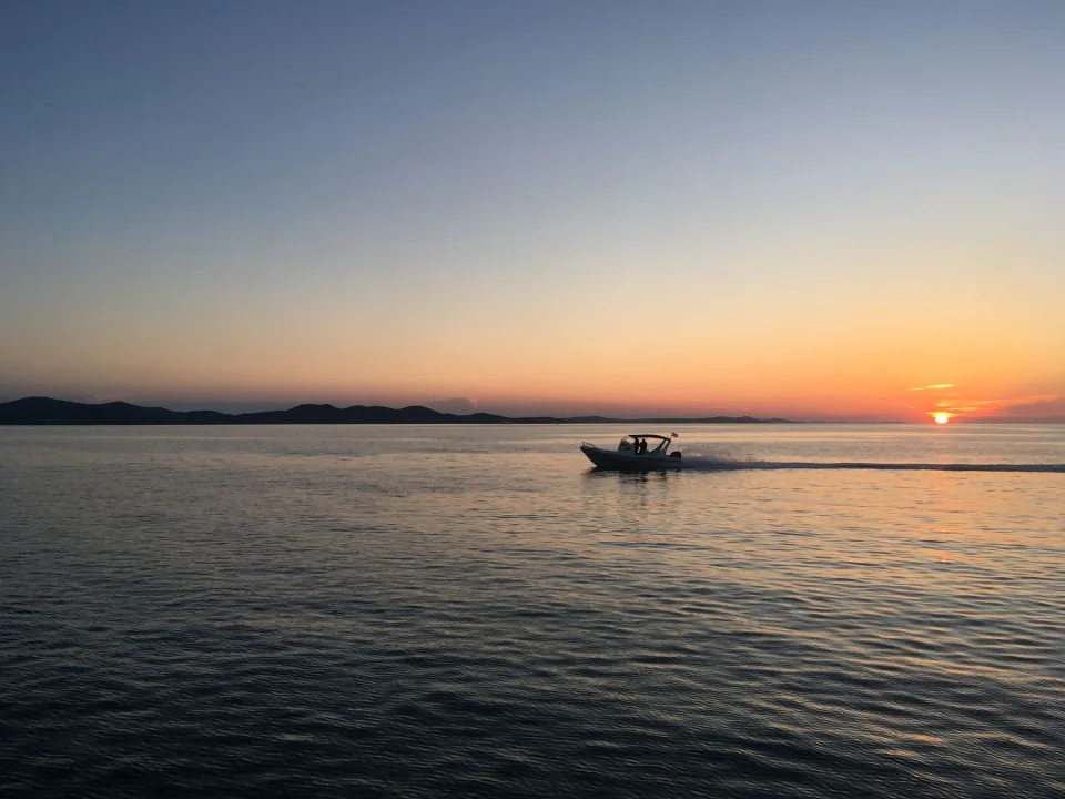 A small motorboat crossing the Adriatic at sunset.