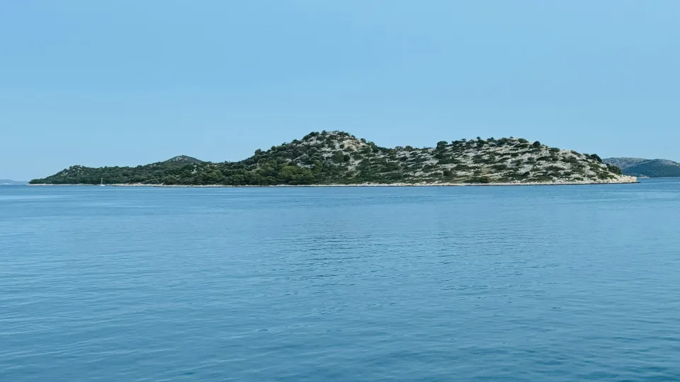 Blue sea and a rocky islet viewed from the coast at Tribunj