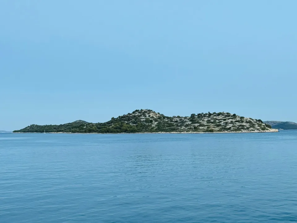 Blue sea and a rocky islet viewed from the coast at Tribunj