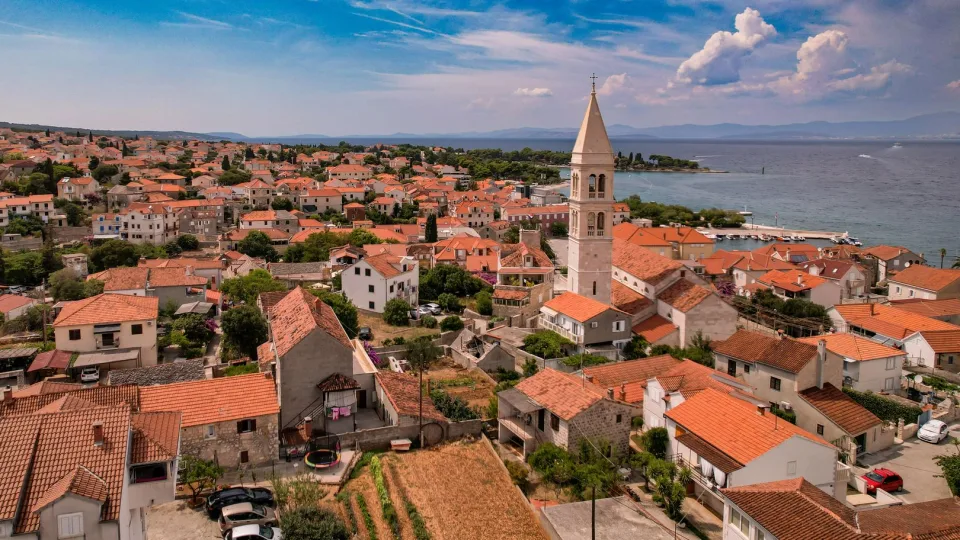 Regional view of coastal rooftops, a church tower and sea at Kaštela