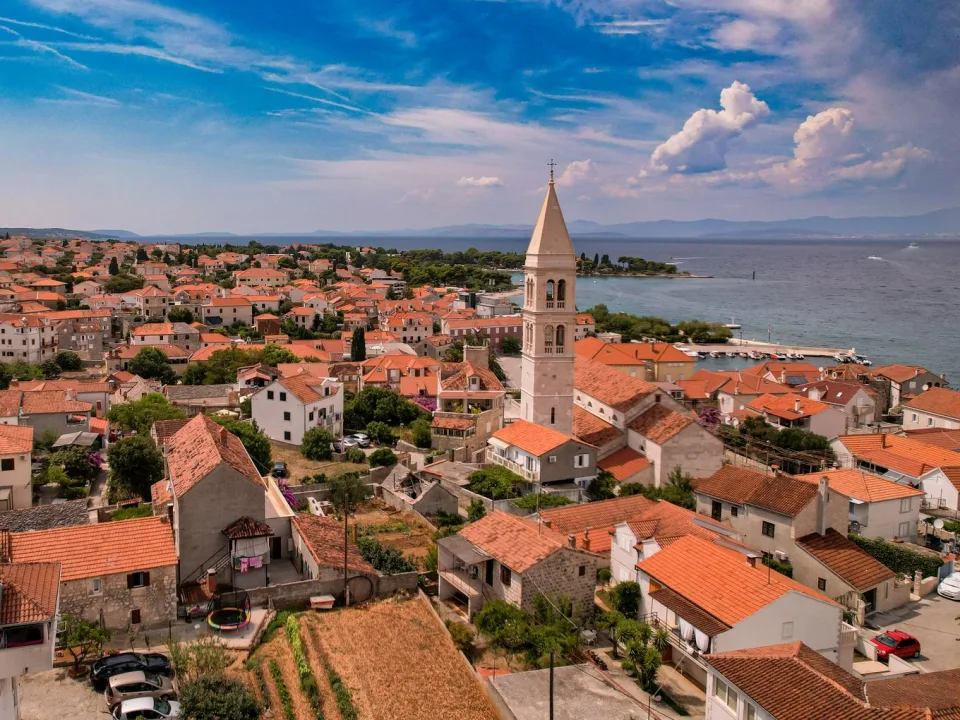 Regional view of coastal rooftops, a church tower and sea at Kaštela