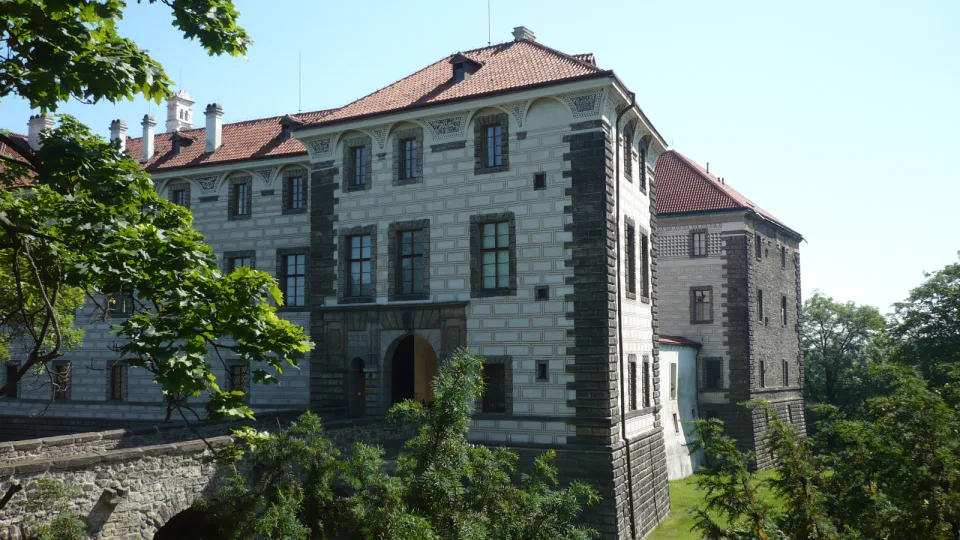 Nelahozeves Castle with a decorated facade, red roof and stone approach bridge