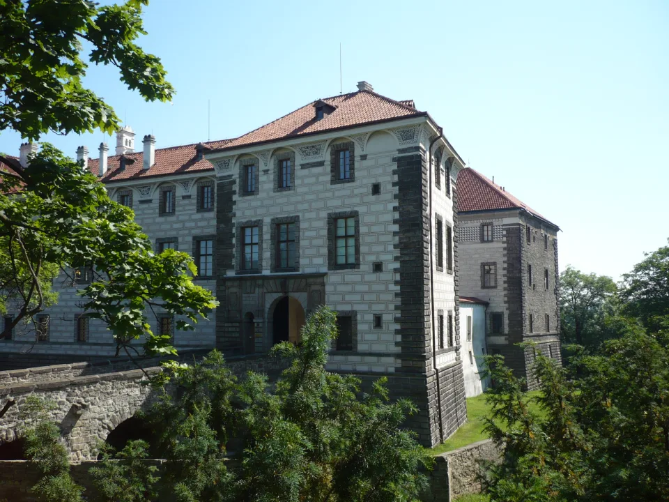 Nelahozeves Castle with a decorated facade, red roof and stone approach bridge