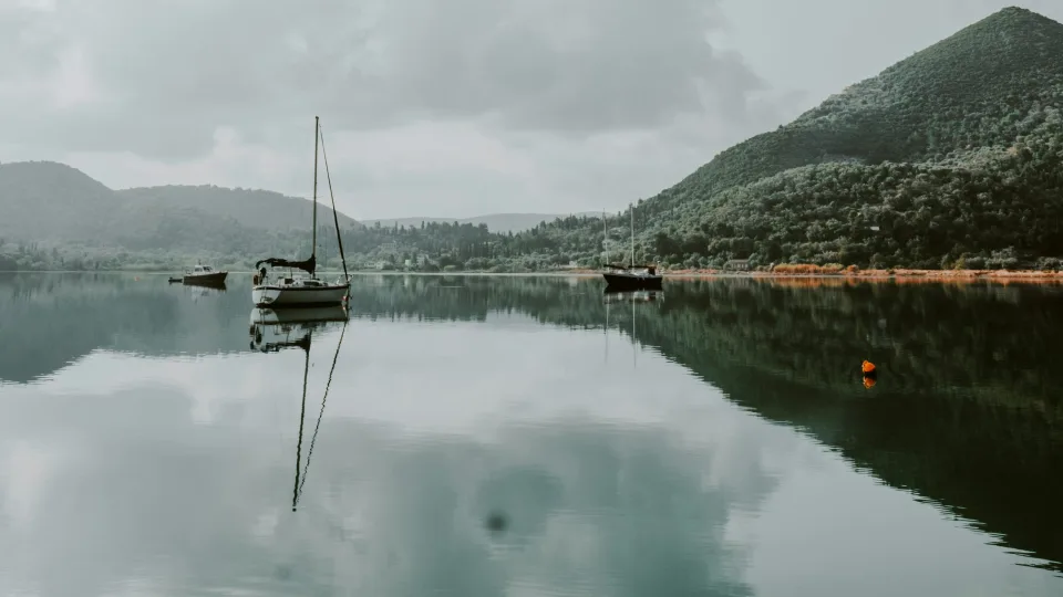 Boats reflected in the water beneath wooded hills near Nydri on Lefkada