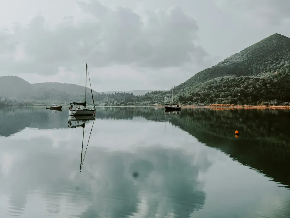 Boats reflected in the water beneath wooded hills near Nydri on Lefkada