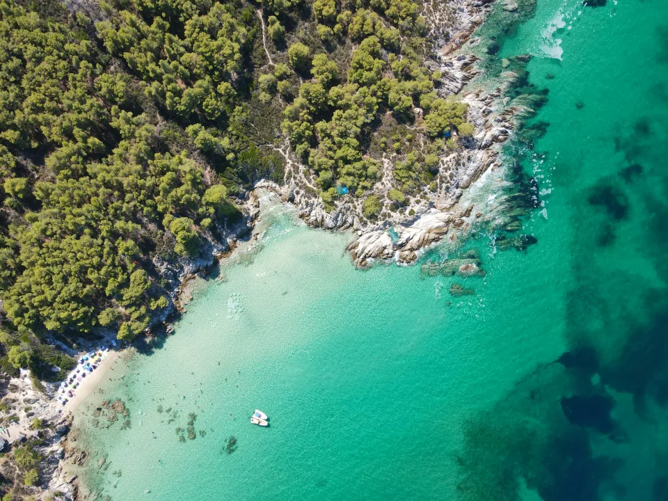 Regional aerial view of pine trees, rocks and turquoise sea at Kavourotrypes on Sithonia