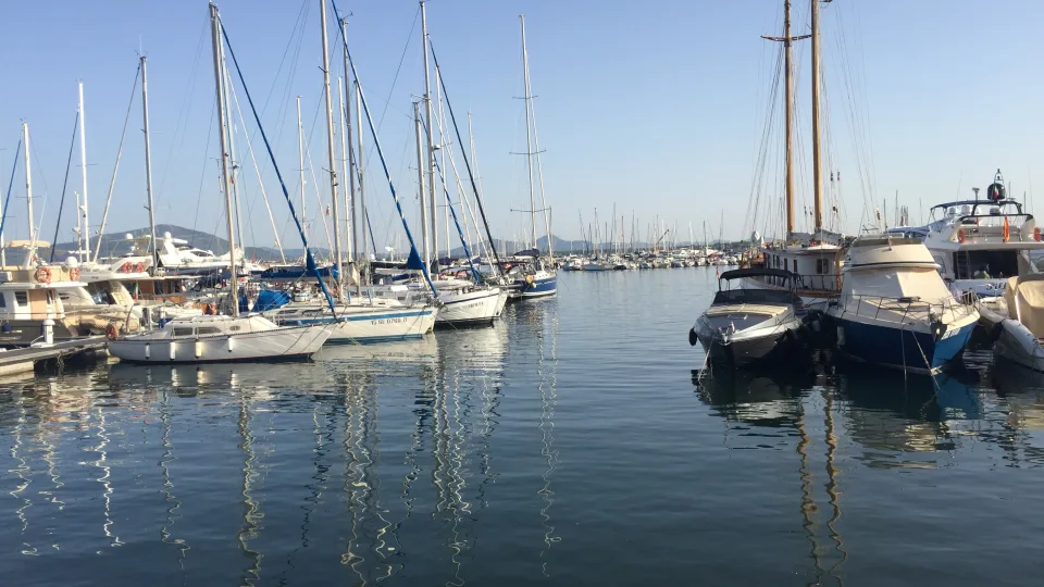 Sailing yachts and motorboats moored around a water channel in Alghero harbour, Sardinia