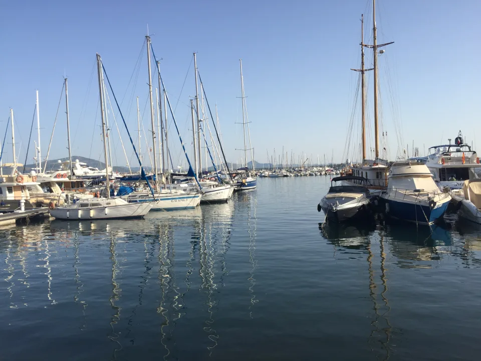 Sailing yachts and motorboats moored around a water channel in Alghero harbour, Sardinia