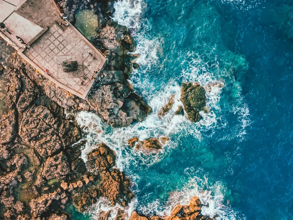 Rocky shoreline and turquoise water at Giardini Naxos