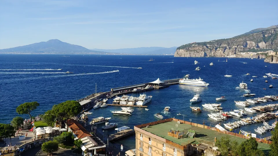 Sorrento harbour with boats, blue water and cliffs around the Gulf of Naples