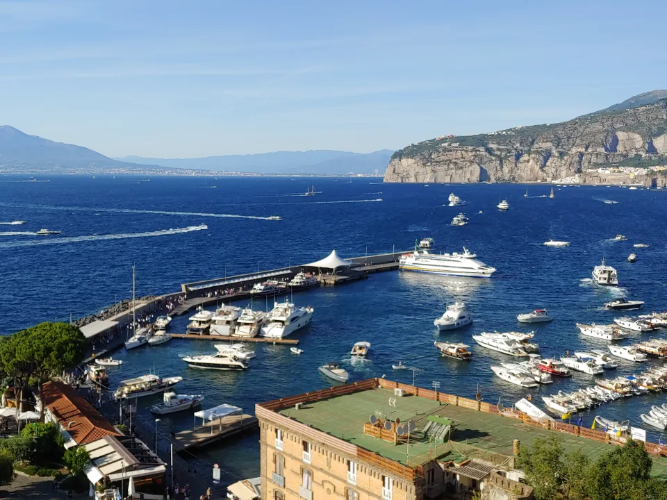 Sorrento harbour with boats, blue water and cliffs around the Gulf of Naples