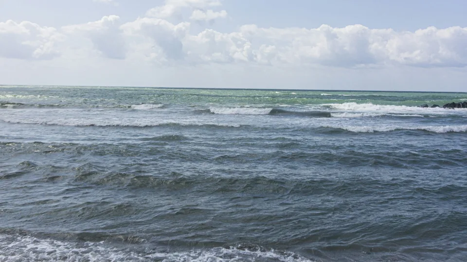 Regional coastal context: waves and blue sky along the shore at Ostia near Isola Sacra