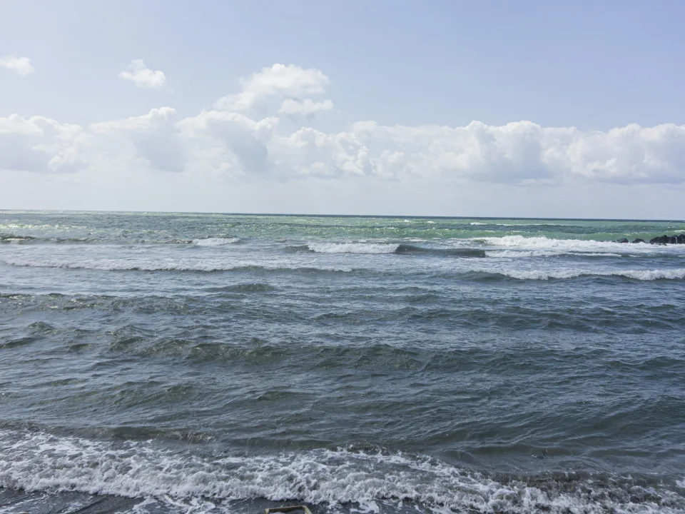 Regional coastal context: waves and blue sky along the shore at Ostia near Isola Sacra