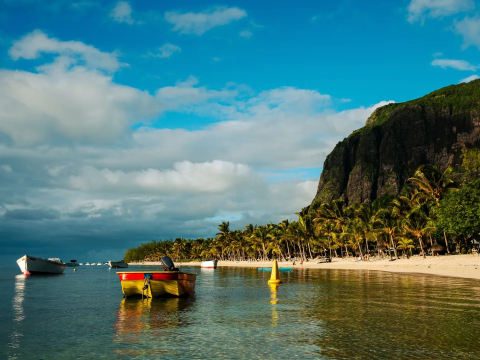 Regional view of boats, palm trees and mountain slopes at Le Morne, Mauritius