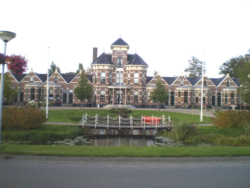 Historic Coopersburg building and garden pond in Akkrum