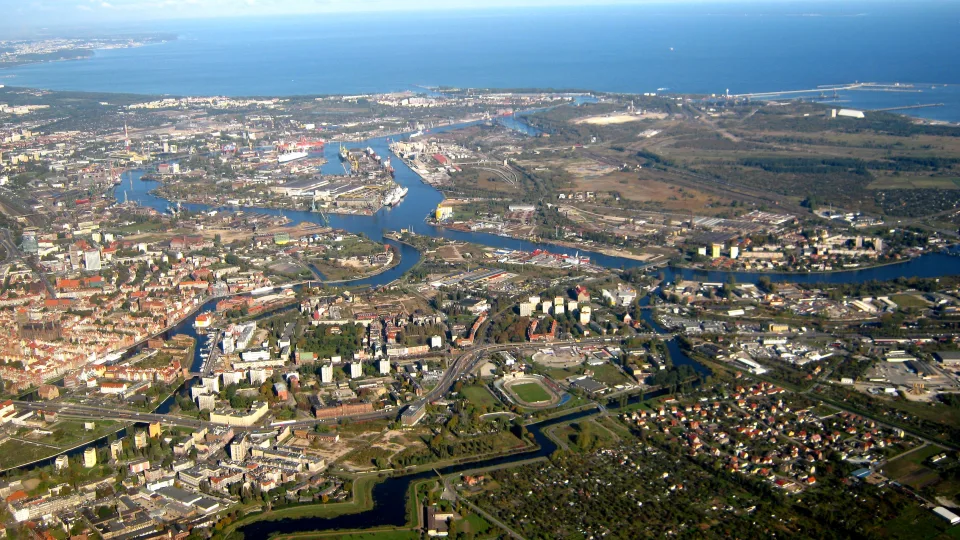 Historical aerial view of Gdańsk city and harbour waterways with the coast beyond