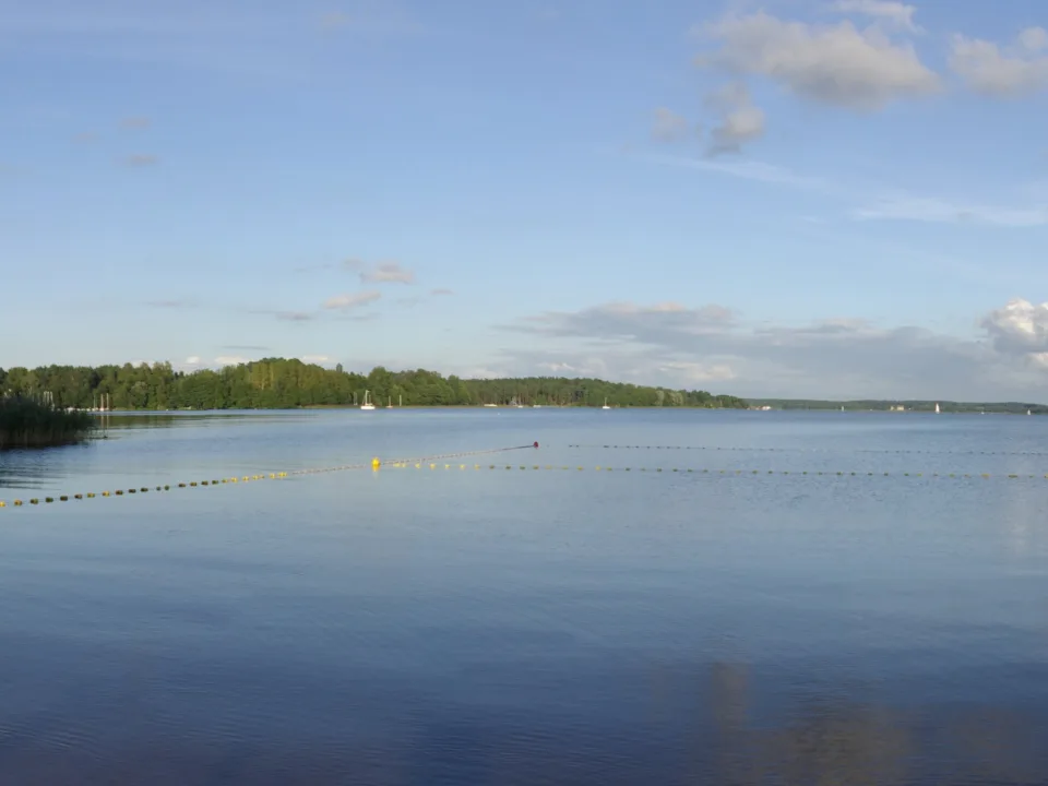 Lake Święcajty near Węgorzewo in Poland, with wooded shores and distant sailboats