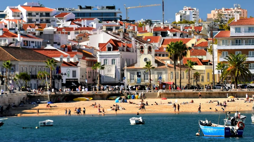 Fishing boats in Cascais bay beside the beach and town buildings in Portugal