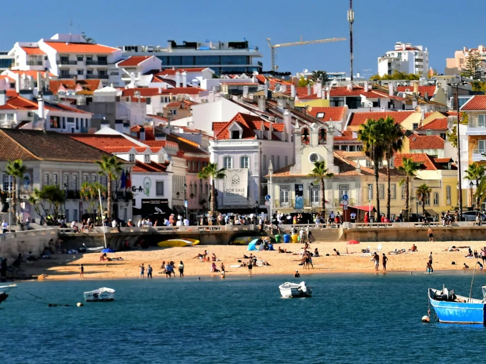 Fishing boats in Cascais bay beside the beach and town buildings in Portugal