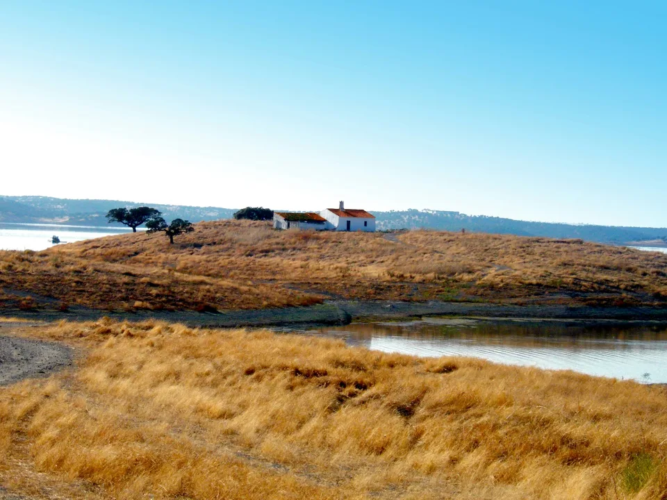 Regional scenery: White house on a dry grassy peninsula beside Alqueva reservoir in Portugal