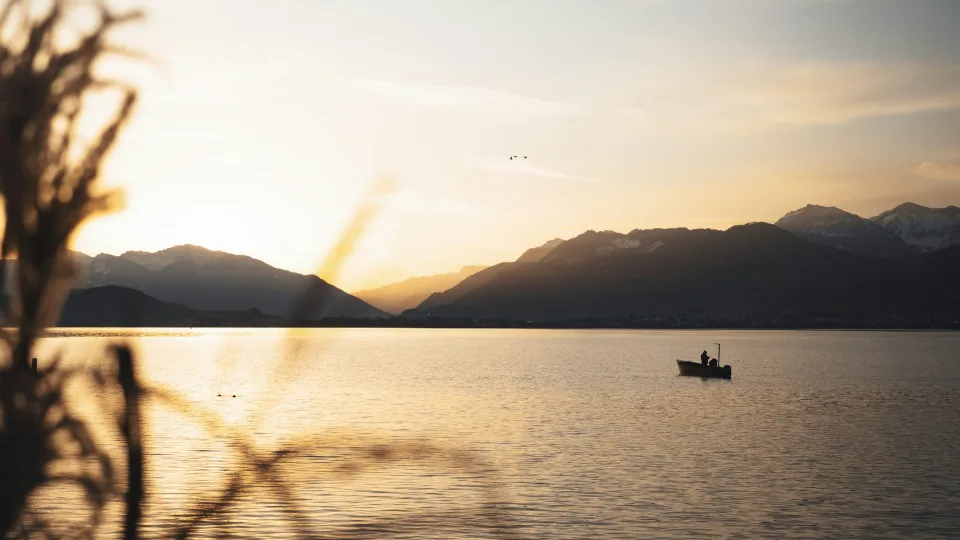 Small boat on a lake with distant mountains at Rapperswil-Jona