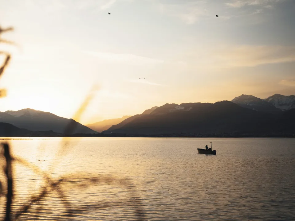 Small boat on a lake with distant mountains at Rapperswil-Jona