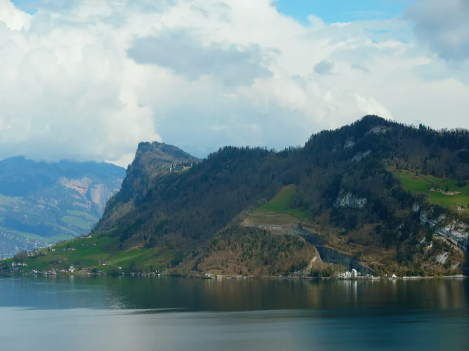 Blue lake below wooded slopes and mountains in Switzerland