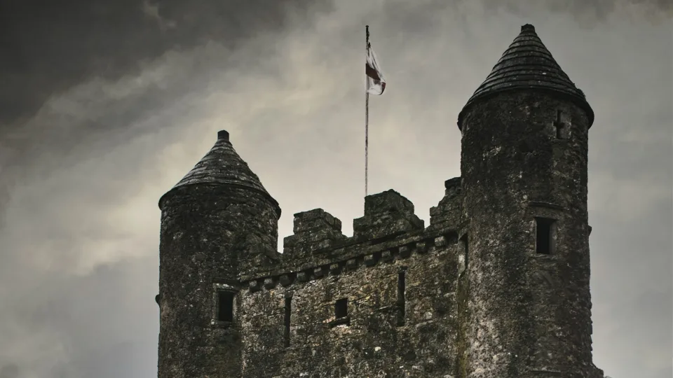Regional shore context: two stone towers and a flag at Enniskillen Castle under a cloudy sky in Northern Ireland