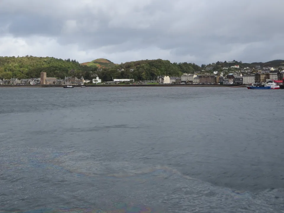 Oban Harbour in western Scotland, with grey water, town waterfront and wooded hills