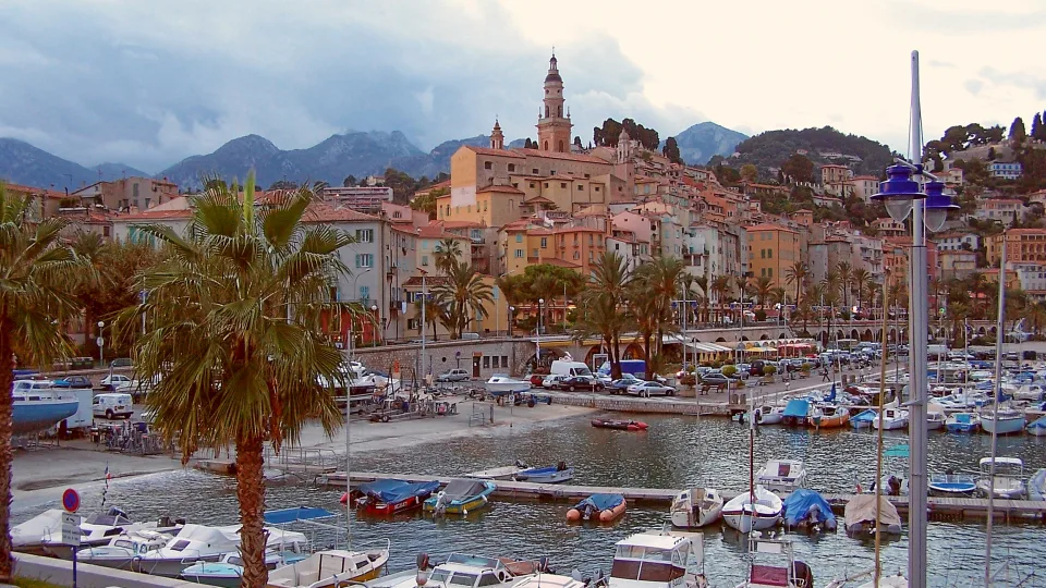 Menton old town, palm trees and boats in its harbour.