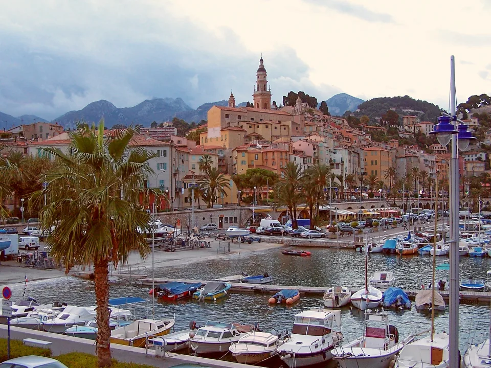 Menton old town, palm trees and boats in its harbour.