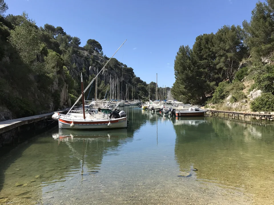 Sailing boats moored between the wooded rocky banks of Port-Miou, Cassis.