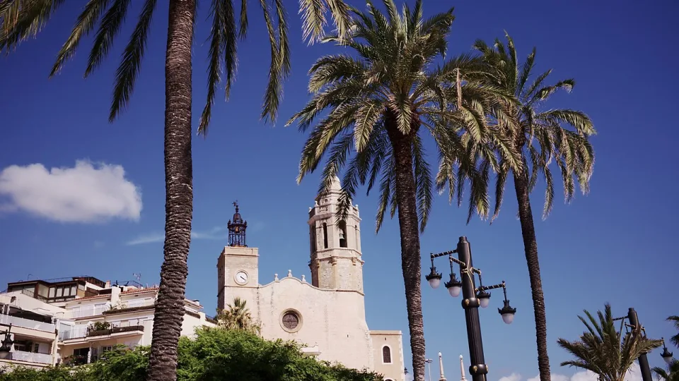 Palm trees and the church on the seafront in Sitges.