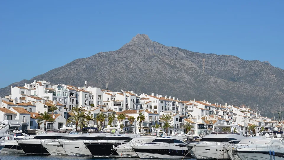 Motor yachts at a marina in Marbella below the coastal mountains.