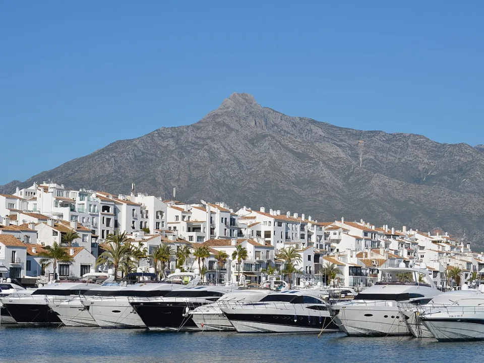Motor yachts at a marina in Marbella below the coastal mountains.