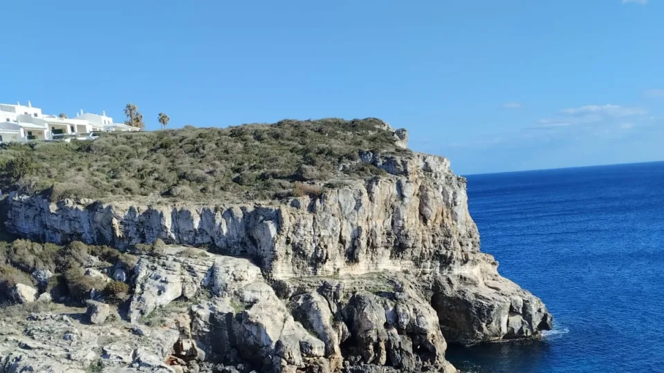 Rocky cliffs and a blue-water inlet at Es Canutells, Menorca.