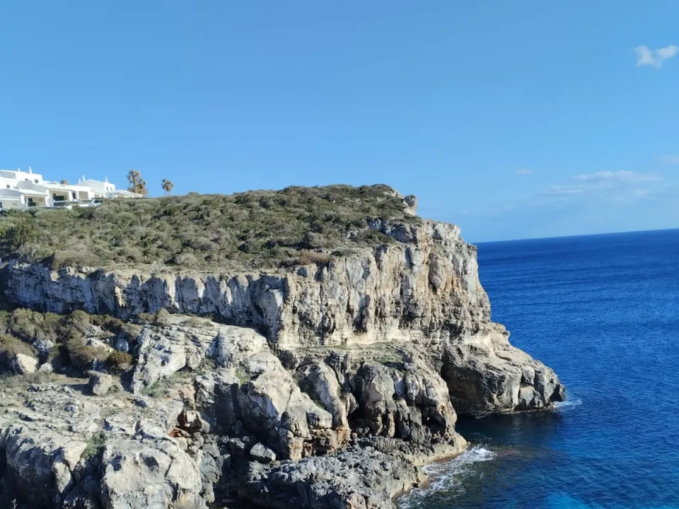 Rocky cliffs and a blue-water inlet at Es Canutells, Menorca.